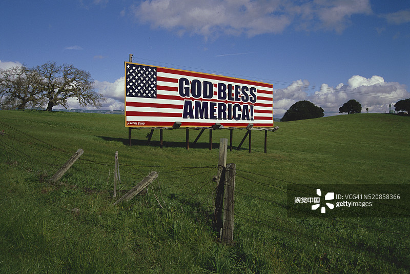 带刺铁丝网围栏上的爱国主题广告牌图片素材