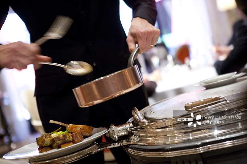 在巴黎雅典娜广场酒店的Alain Ducasse餐厅，服务员在午餐时段提供羊肉图片素材