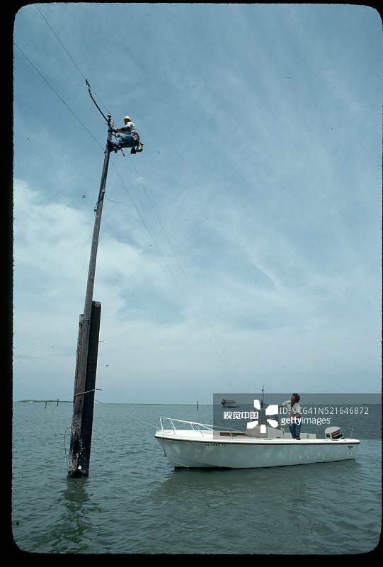 线路工在水中的电线杆上工作图片素材