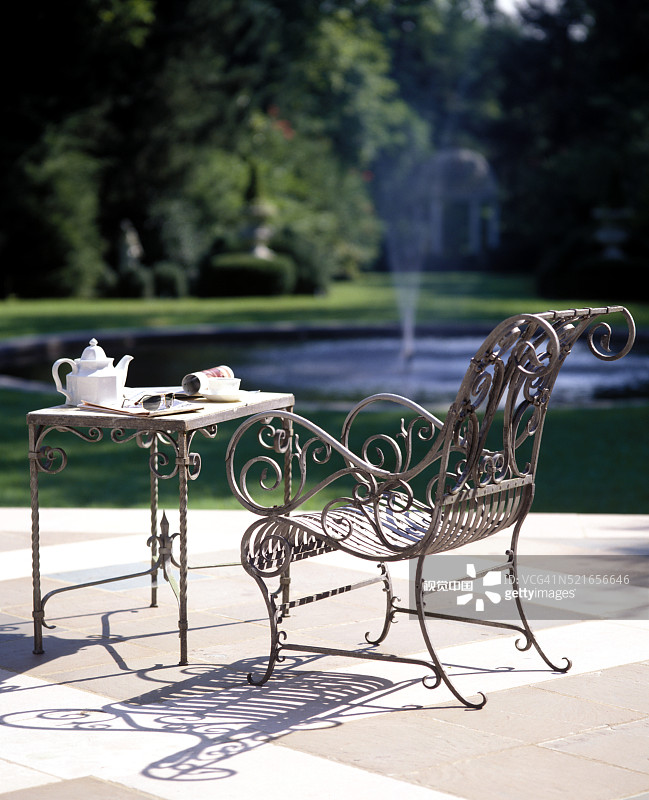 花园池塘前华丽的锻铁桌椅图片素材