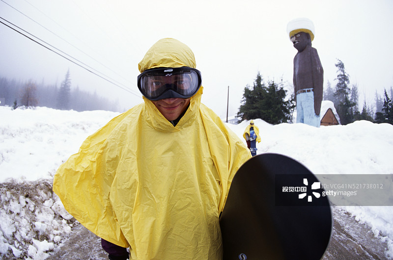 身穿黄色雨披的单板滑雪者图片素材