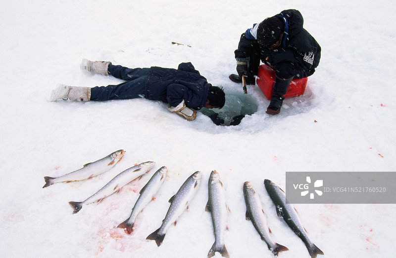 爱斯基摩人在冰洞中捕鱼，捕捉北极红点鲑。图片素材