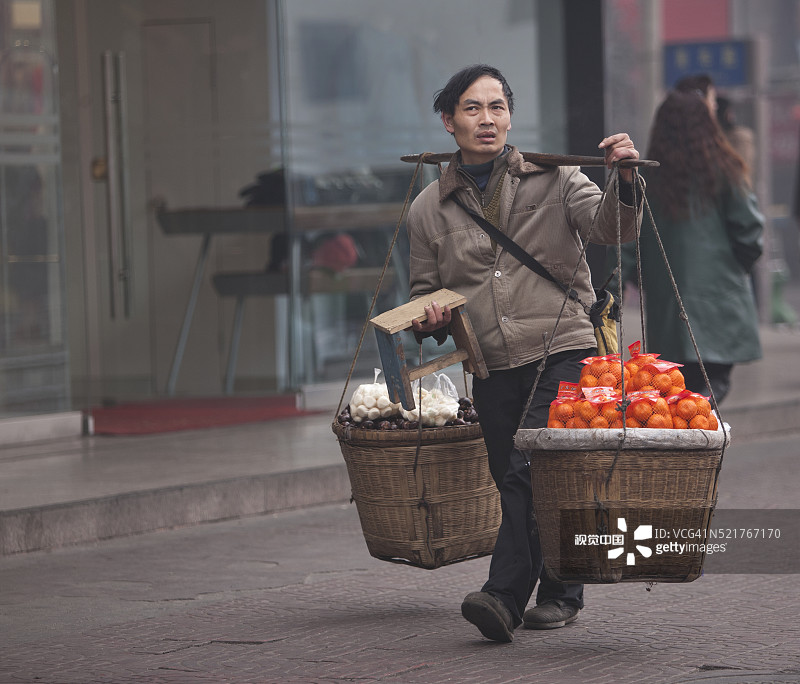 农民用竹肩挑着篮子运送水果图片素材