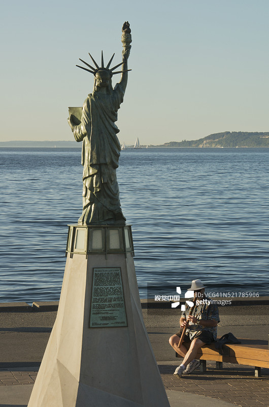 男子在迷你“自由女神像”下吹长笛图片素材