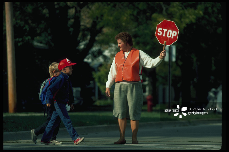 男孩们走过学校的交通协管员图片素材