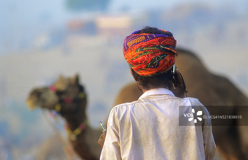 印度骆驼节期间拨打手机的牧驼人图片素材