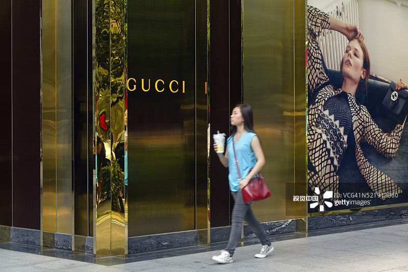 一位年轻女子走过中国台湾台北信义区的Gucci商店图片素材