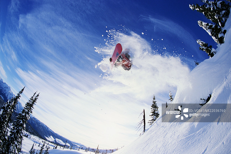 滑雪板运动员在雪山上随着滑板跳跃图片素材
