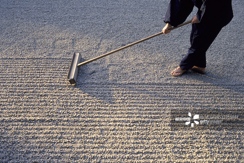 禅宗花园中耙砾石的僧侣图片素材