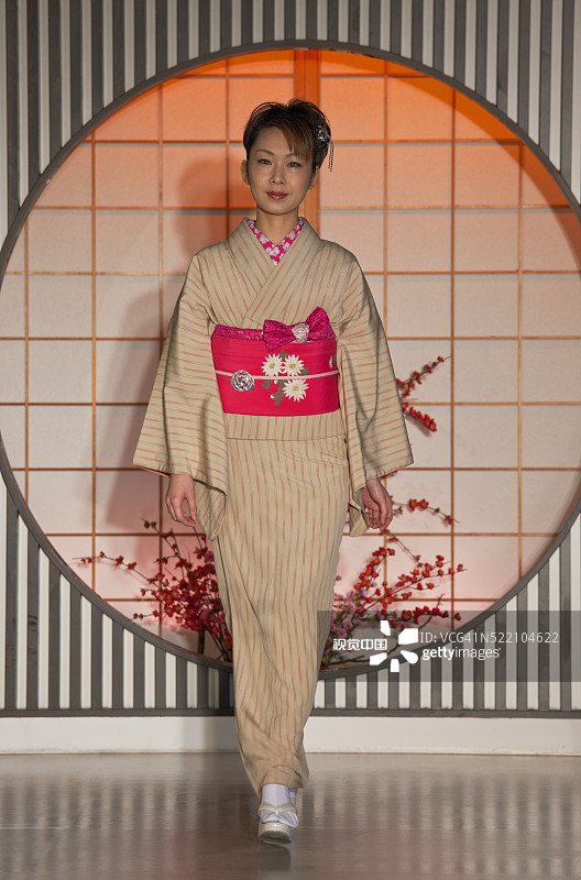 一位年轻的日本女人在京都西阵纺织中心展示传统和服与丝绸腰带图片素材