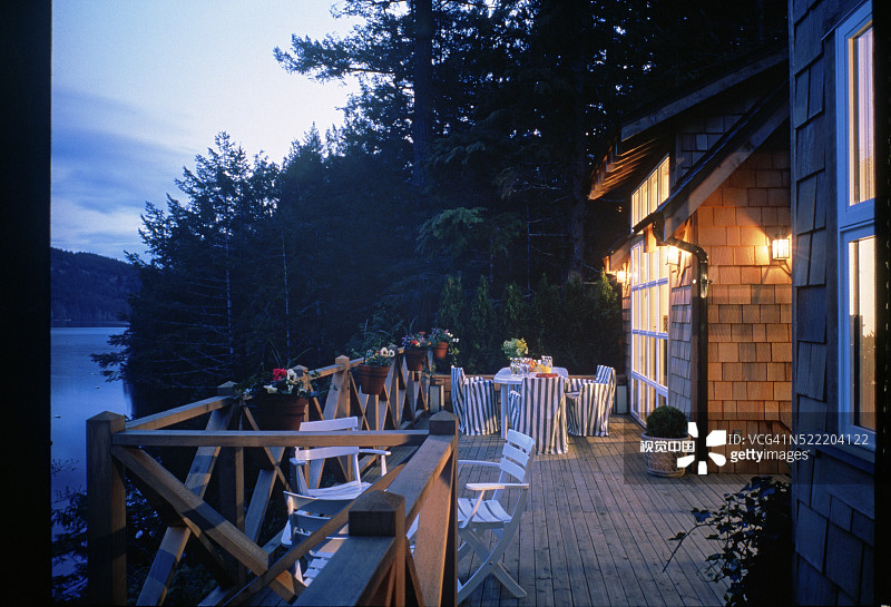 黄昏时分，带桌椅的平台俯瞰着有山脉背景的湖泊图片素材