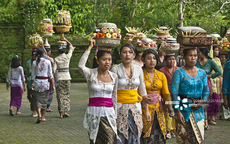 在印度尼西亚巴厘岛，妇女们在加隆安节期间向提尔塔埃普神庙供奉水果、鲜花和糕点图片素材