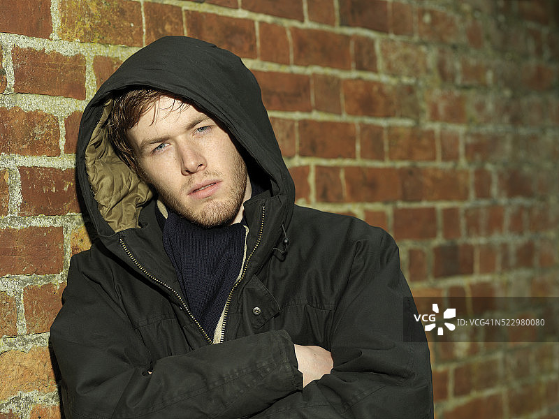 倚靠在砖墙上的年轻男人图片素材