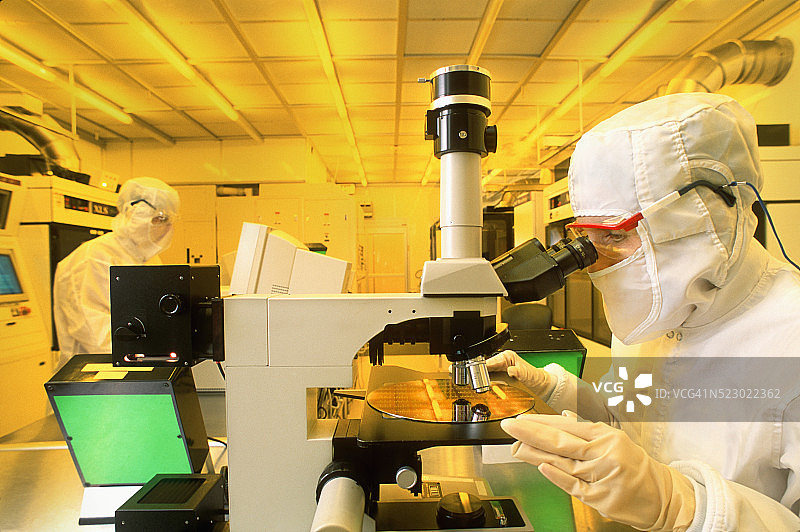 技术员在洁净室用显微镜检查含芯片的硅晶圆图片素材