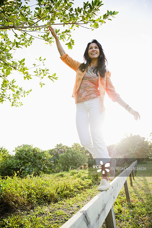 在木栅栏上保持平衡的女人图片素材