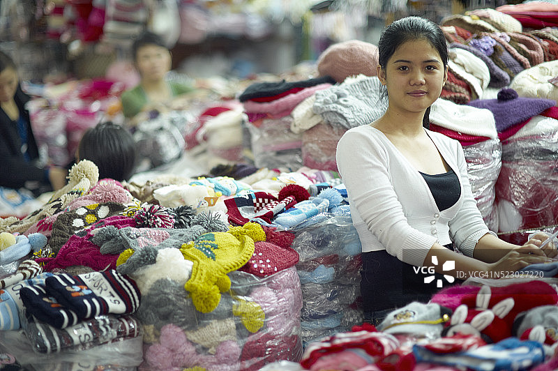 年轻女子站在市场服装堆旁的肖像图片素材