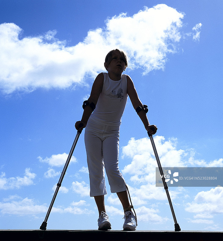 11岁戴着腿部支架的残疾女孩使用肘部拐杖图片素材