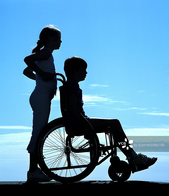 坐在轮椅上被健全儿童推动的残疾儿童图片素材