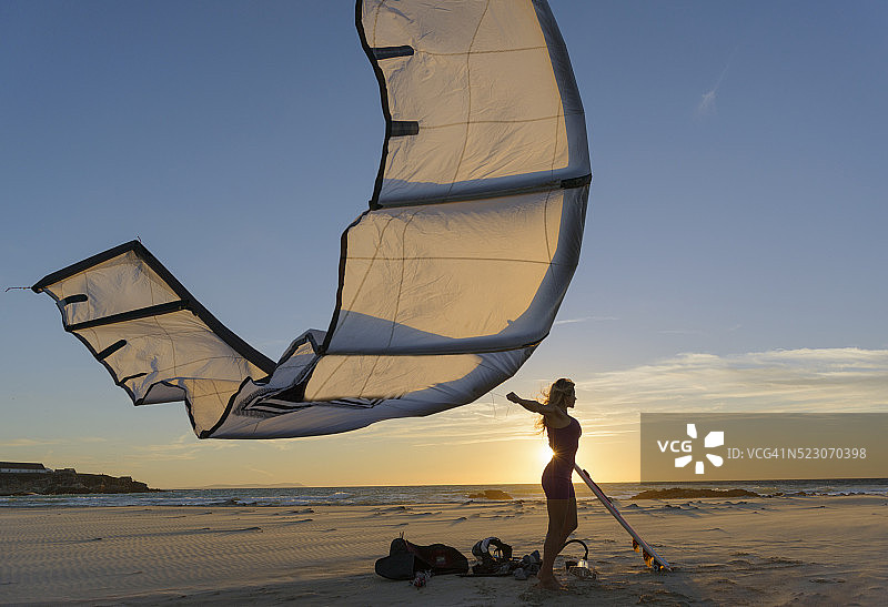 女人在西班牙安达卢西亚加的斯科斯塔德拉卢斯塔里法日落时放风筝图片素材
