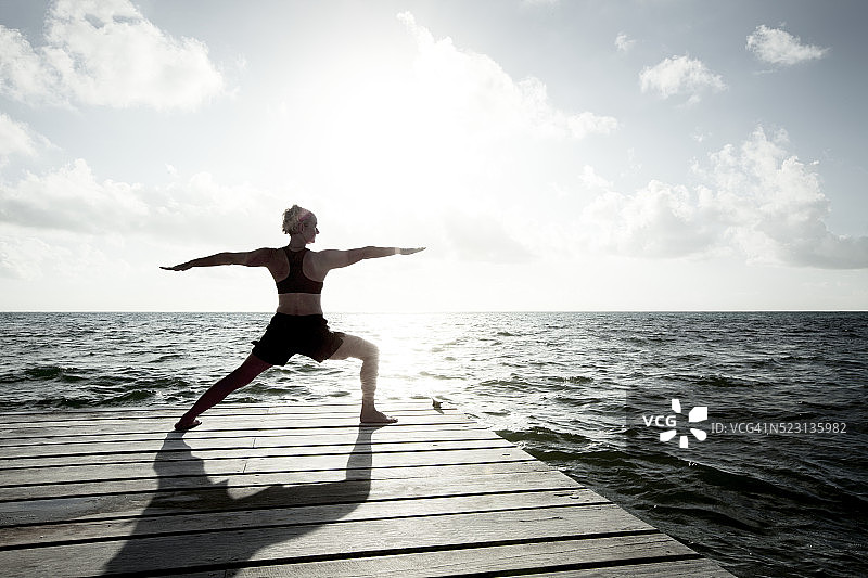 在伯利兹度假的女人在加勒比海附近的码头上练习瑜伽图片素材