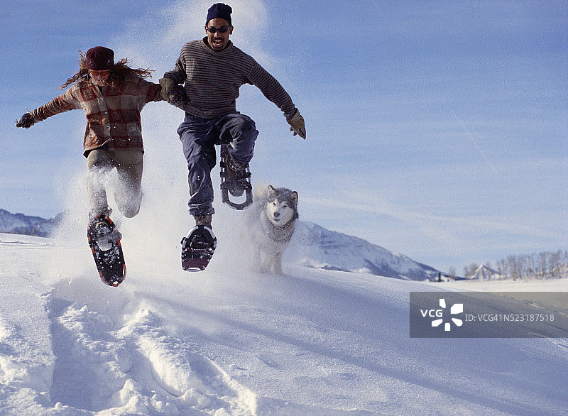 情侣穿着雪鞋跳跃图片素材