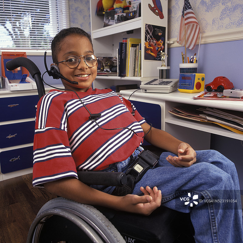 坐在轮椅上，使用耳机电话的男孩图片素材