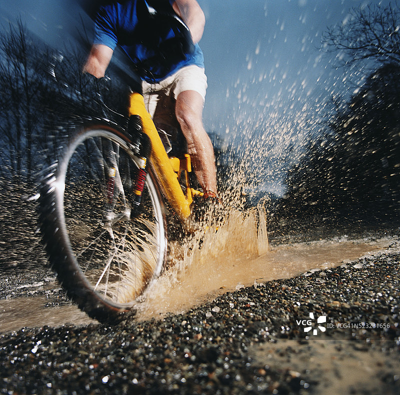 骑自行车的人穿过水坑图片素材