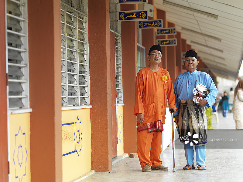 两名穿着传统服装的男子站在学校前图片素材