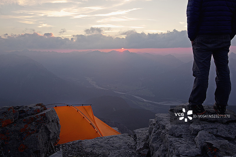 男子站在靠近帐篷的较高岩石上，奥地利蒂罗尔图片素材