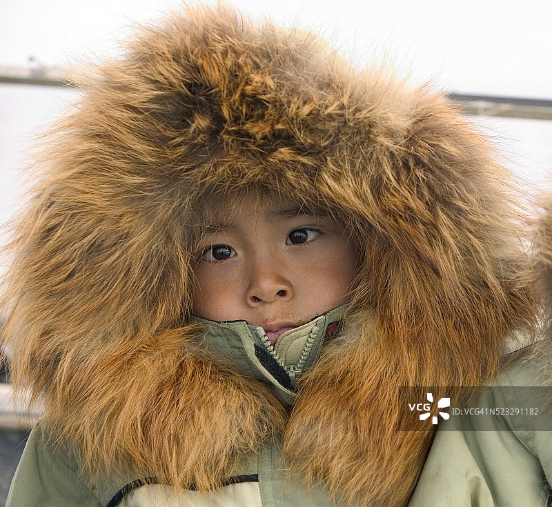 身穿红色狐狸皮衬里外套的因纽特男孩图片素材