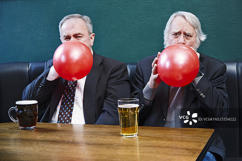 年长的男人坐在酒吧里吹气球图片素材