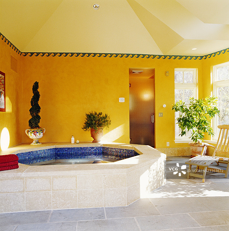 浴室内的八角浴缸旁的木椅图片素材