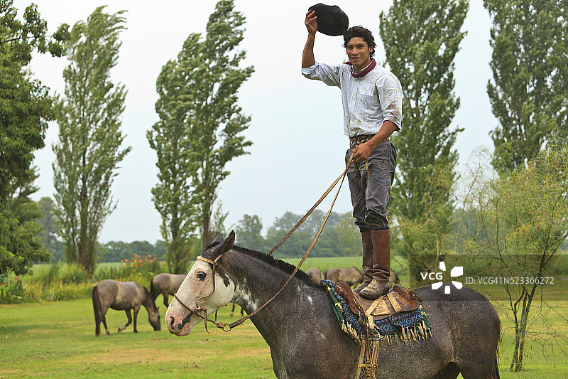 马背上站立的高乔人，手持帽子图片素材