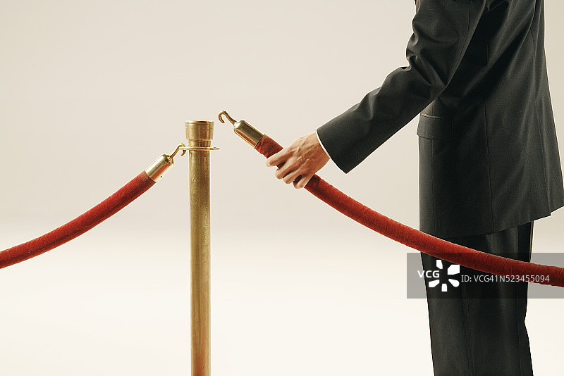 男人拿着天鹅绒绳图片素材