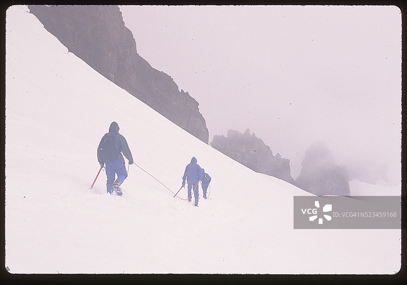 登山者行走在贝克山云雾缭绕的山峰图片素材