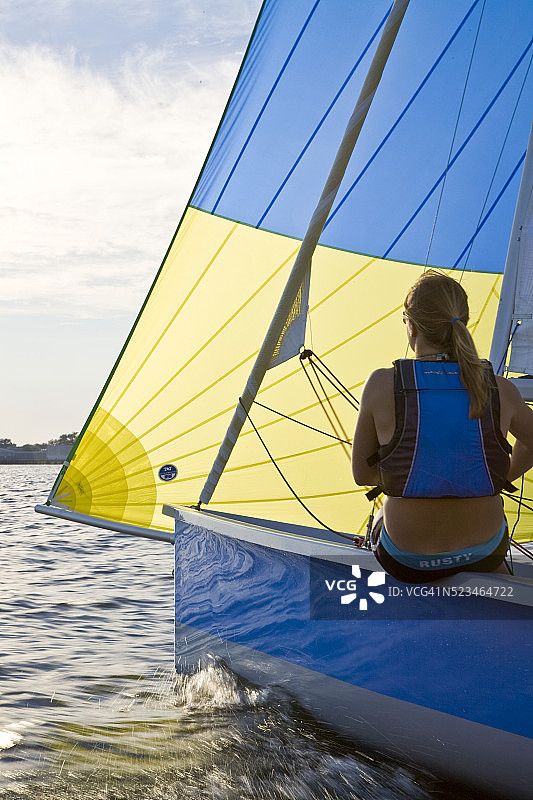 年轻女子在先锋游牧帆船上调整三角帆图片素材