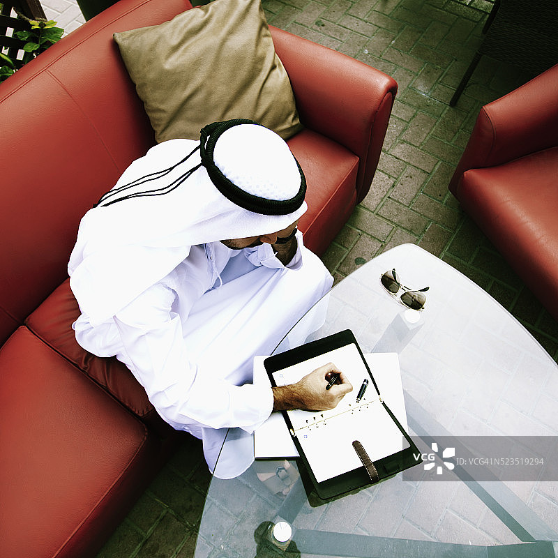 在迪拜户外咖啡馆做笔记的阿拉伯商人，阿拉伯联合酋长国图片素材