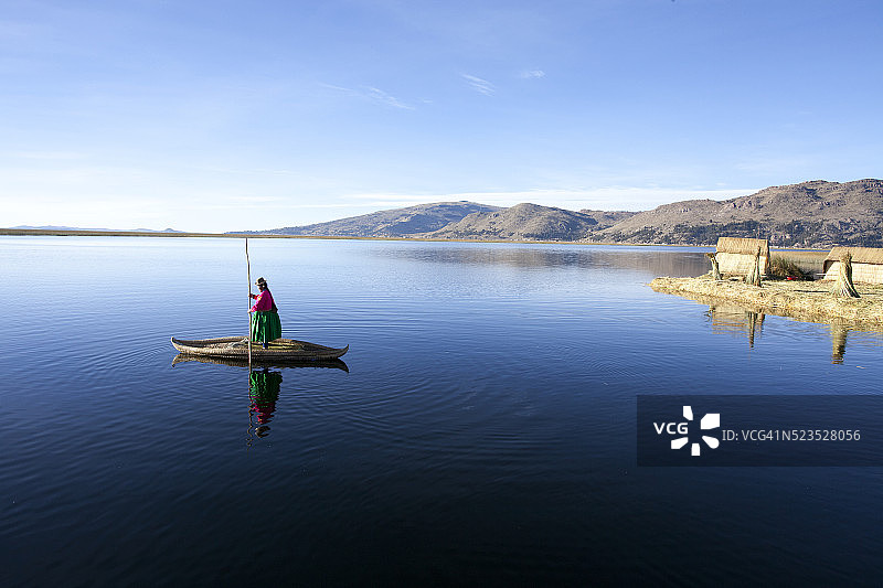 穿着传统服装的女人乘坐传统芦苇船。秘鲁普诺的的喀喀湖乌罗什群岛。图片素材