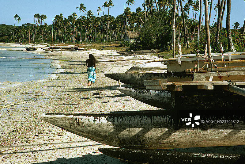 在新喀里多尼亚的海滩上行走，有浮筒船图片素材