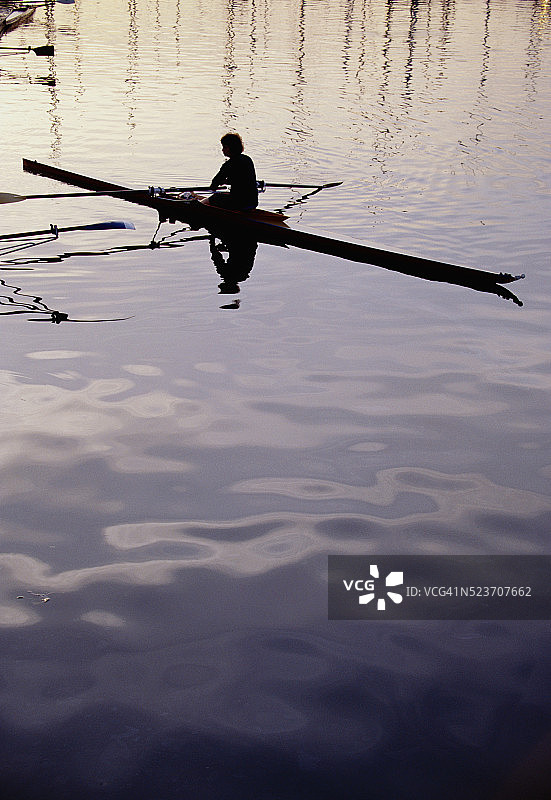 平静水面上单人划桨运动员的剪影图片素材