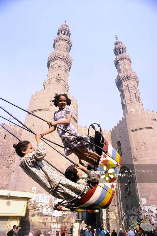 孩子们在清真寺前的秋千上玩耍图片素材