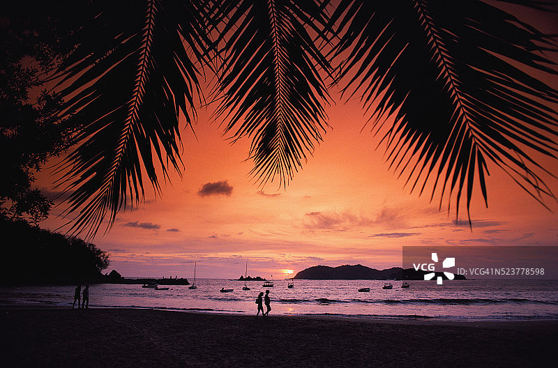 情侣在日落时分在海滩上散步图片素材