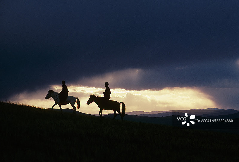 戈壁日落下的骑马者图片素材