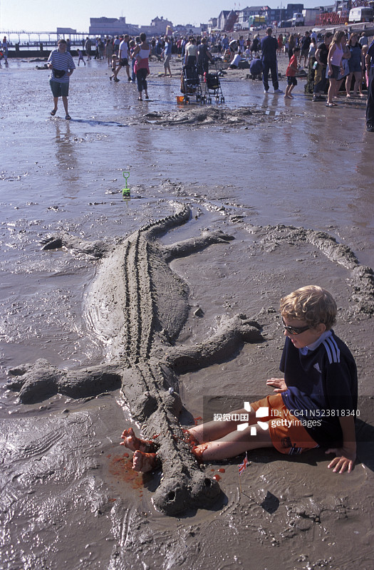 男孩和他的沙鳄鱼在沙滩上图片素材
