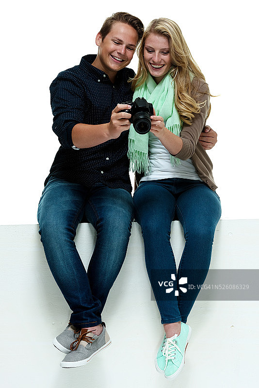 坐在箱子上看着相机的愉快情侣图片素材