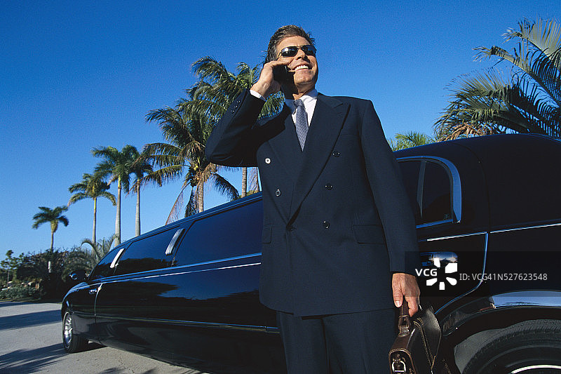 在豪华轿车附近的商人，正在使用手机图片素材