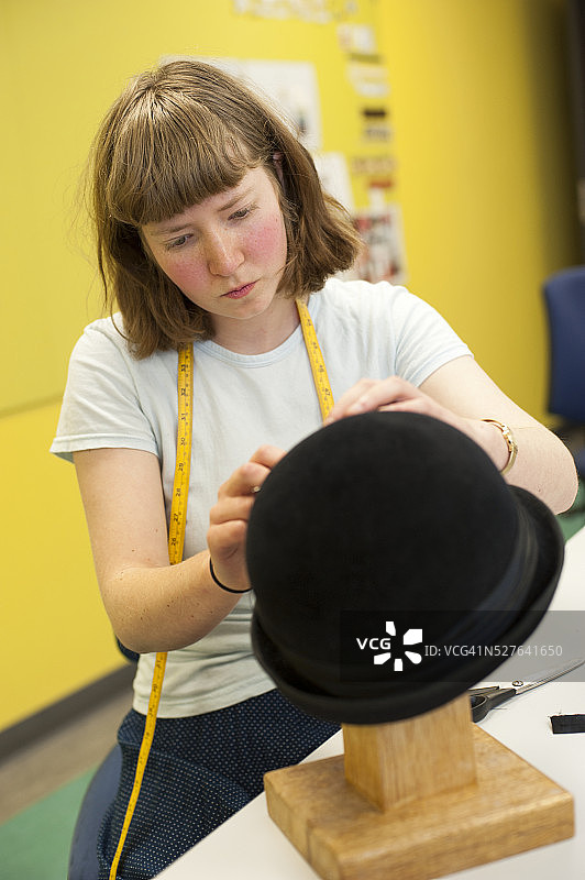 在工作坊里制作帽子的女学生图片素材