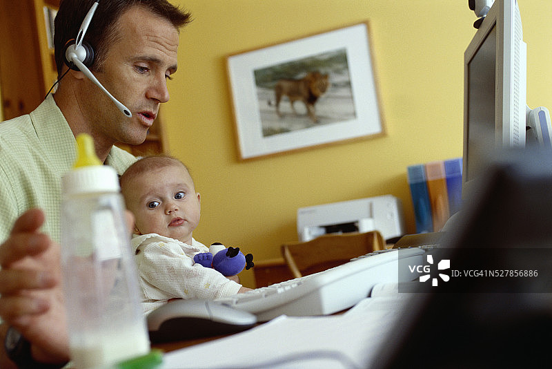 抱着婴儿使用电话耳机图片素材