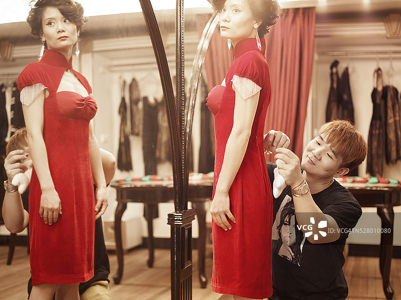 服装设计师陆坤为模特试穿旗袍风格现代礼服图片素材