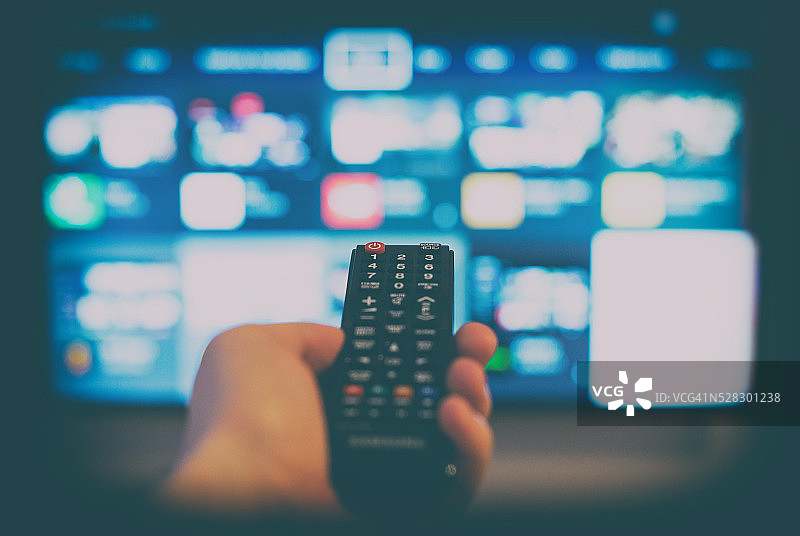 男人手拿着电视遥控器图片素材